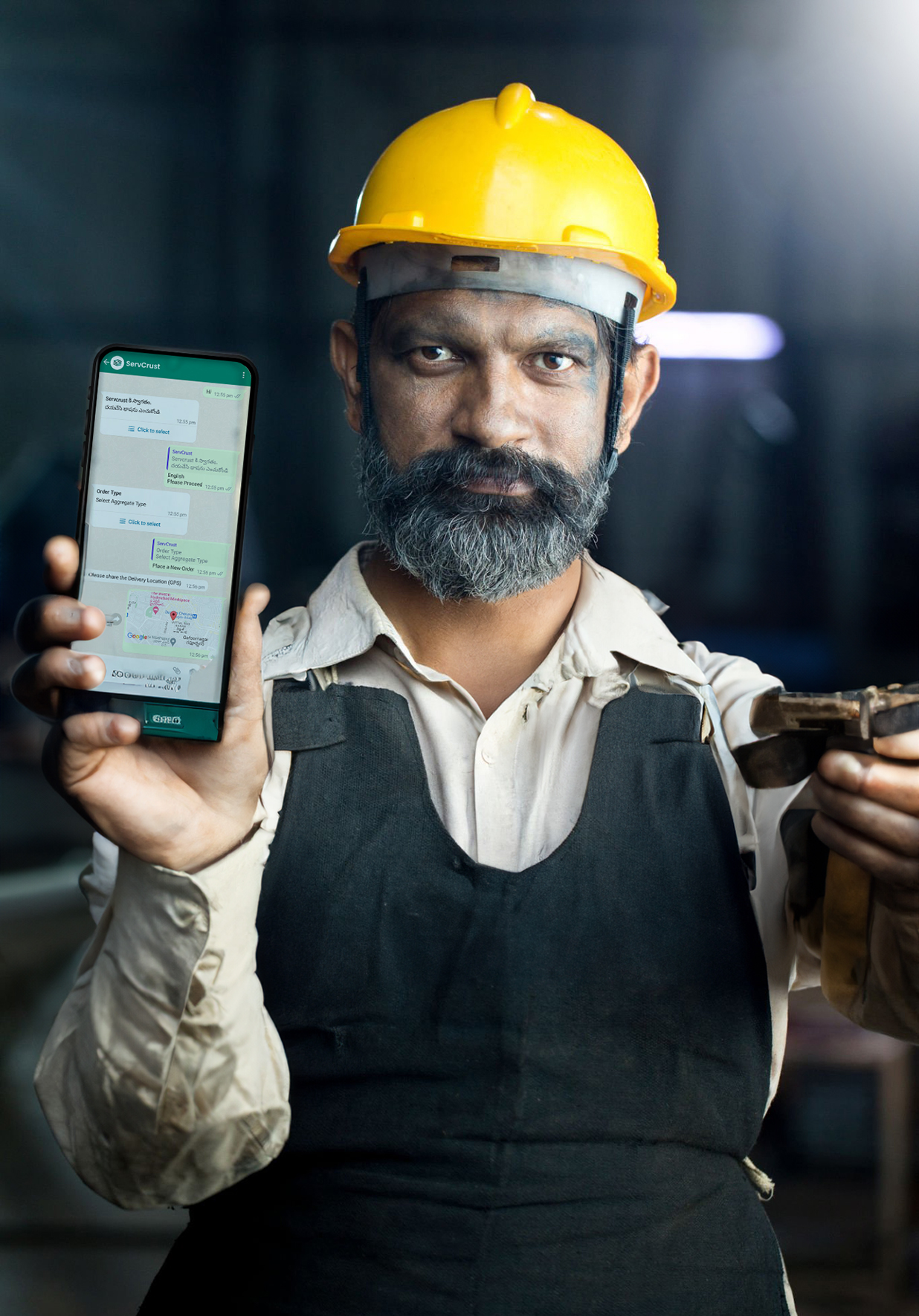 Happy industrial worker showing mobile phone at factory